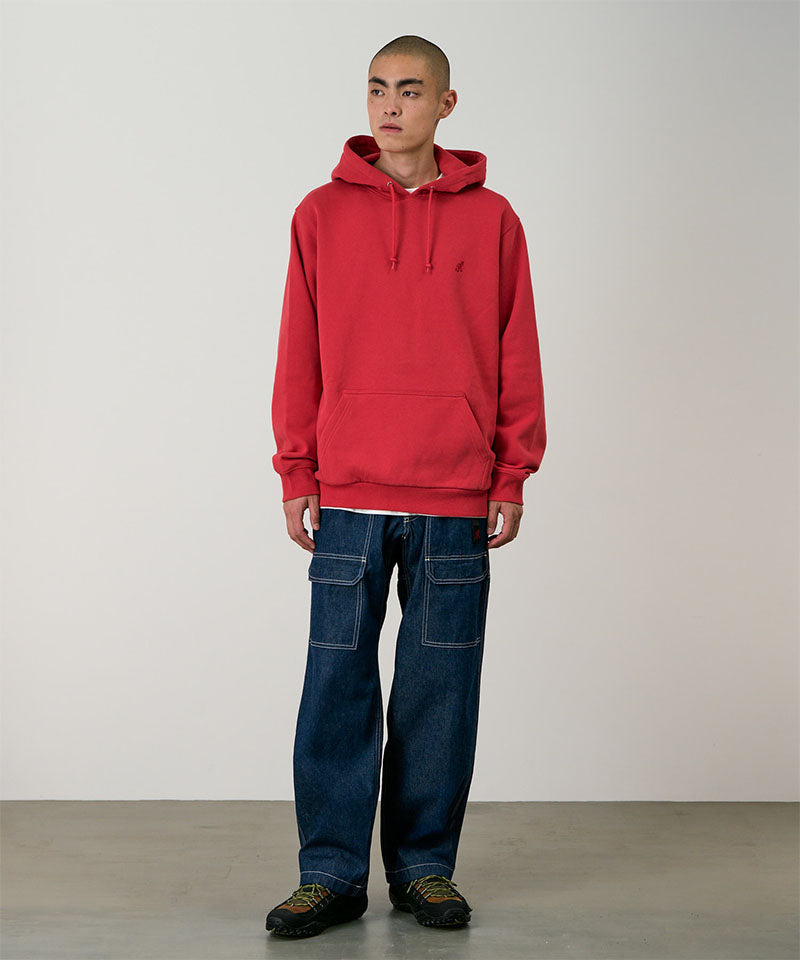 Model wearing rinsed indigo Gramicci Denim EQT Pant and a red hoodie on a light-tone background.