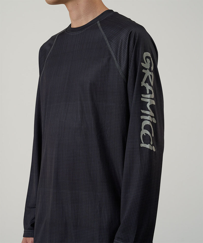 Model wearing a Gramicci black UPF Shield S/S Top with a sleeve graphic against a light-tone background.