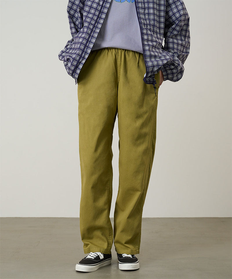Model wearing grass colored Gramicci Swell Pant and a plaid jacket on a light-tone background.