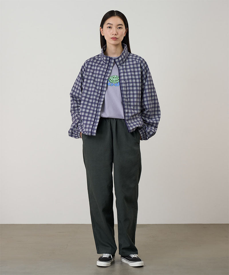 Model wearing shadow colored Gramicci Swell Pant and a plaid jacket on a light-tone background.