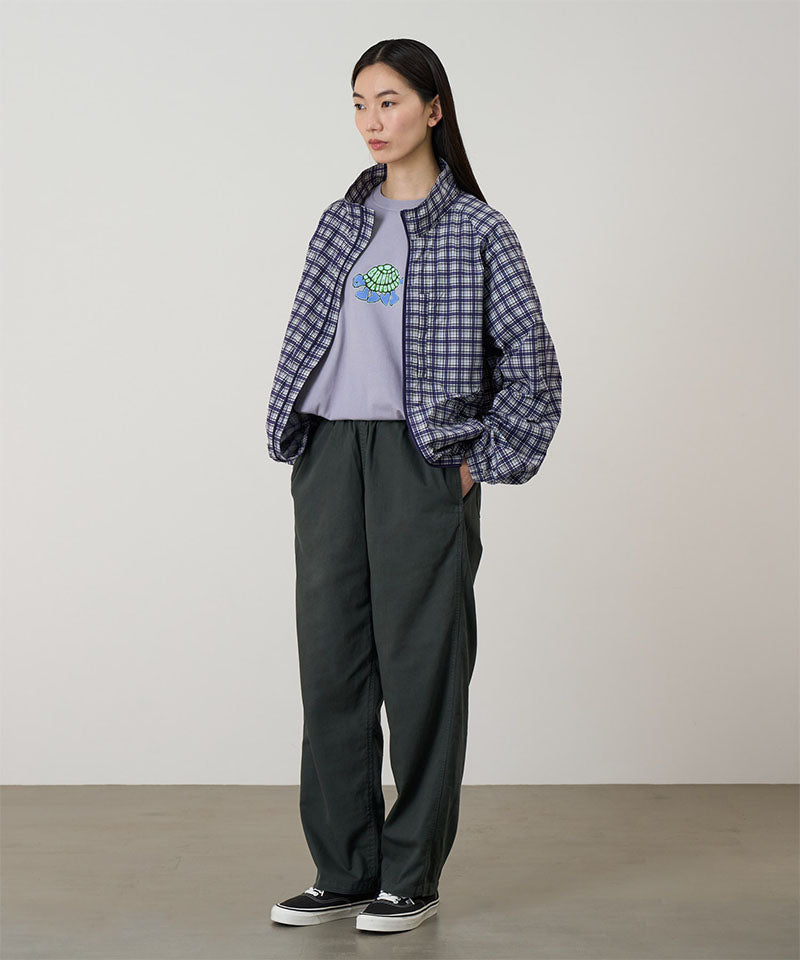 Model wearing shadow colored Gramicci Swell Pant and a plaid jacket on a light-tone background.