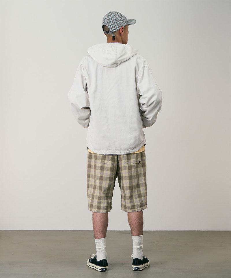 Back view of a model wearing shadow plaid colored Gramicci Swell Short Shadow Plaid and a off-white jacket on a light-tone background.