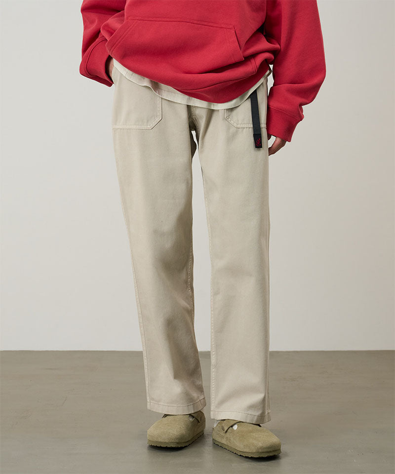 Model wearing sand pigment colored Gramicci Women's Brooks Pants and a red hoodie on a light-tone background.