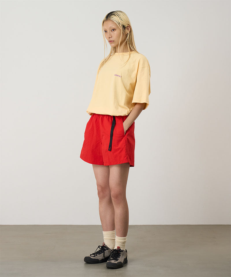Model wearing burnt orange Gramicci Women's Nylon Active Short and a yellow shirt on a light-tone background.