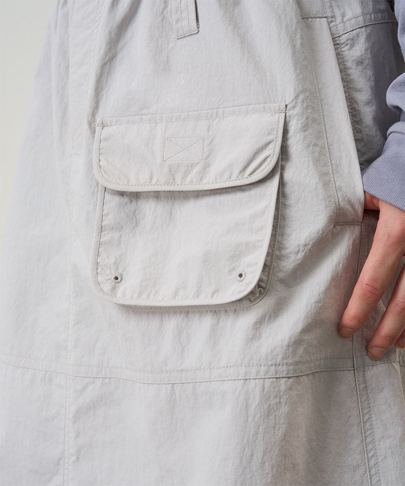 Close-up view of an ecru colored Gramicci Nylon Utility Skirt pocket in on a light-tone background.