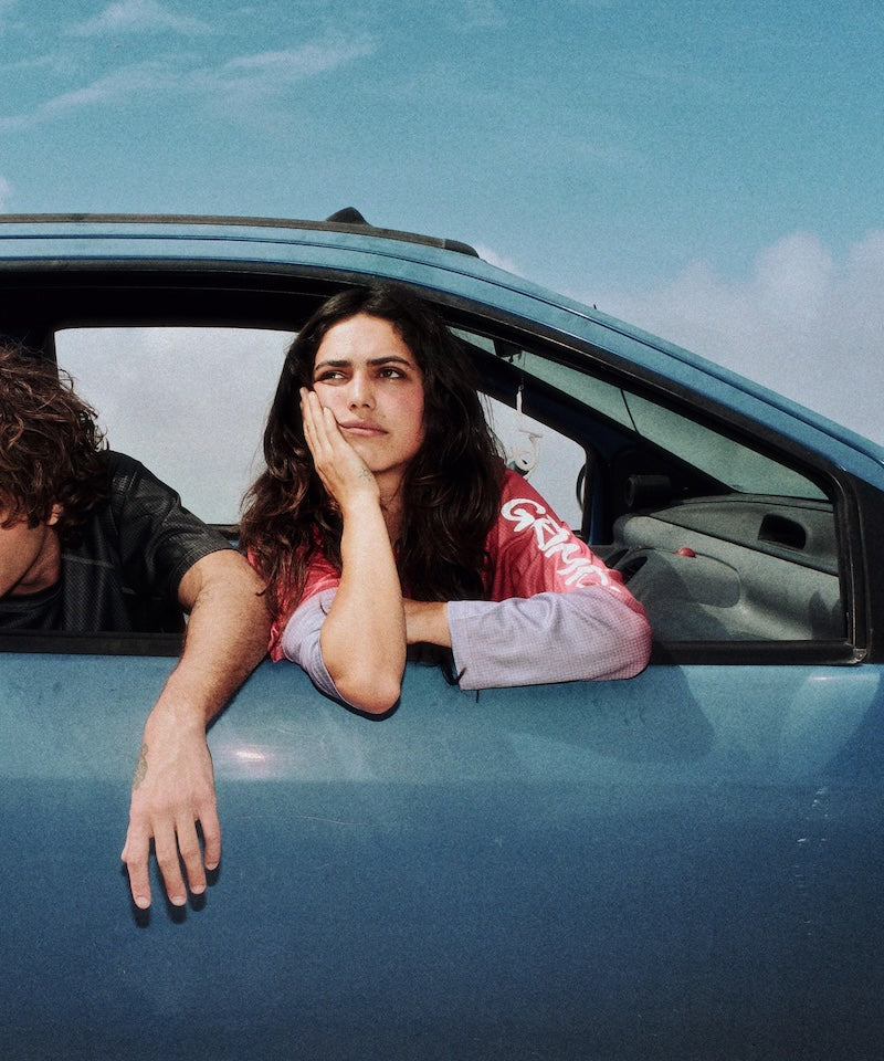 Two people in a car with one person looking out the window.