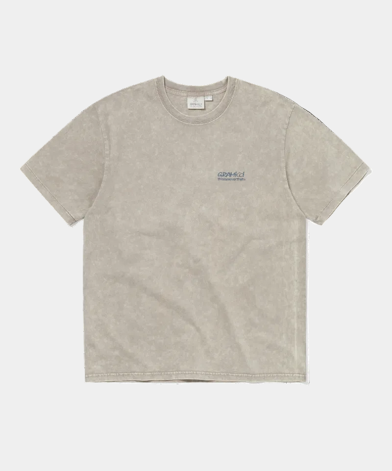 A light beige mineral-wash short-sleeve t-shirt with a small dark blue 'GRAMICCI' graphic on the left chest, displayed flat against a solid white background.