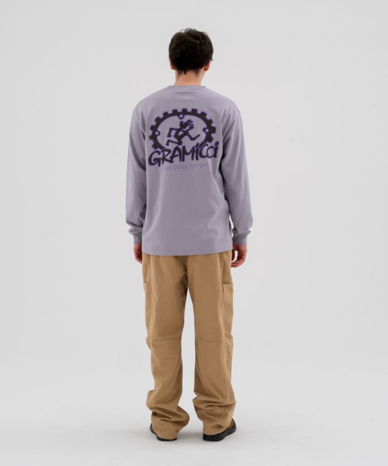 Back view of a model wearing beige Gramicci Voyager Pants and a lavender Gramicci Equipped Dirt Long-Sleeve-Tee on a light-tone background.
