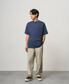 Model wearing a navy Gramicci One Point Tee and beige pants on a light-tone background.