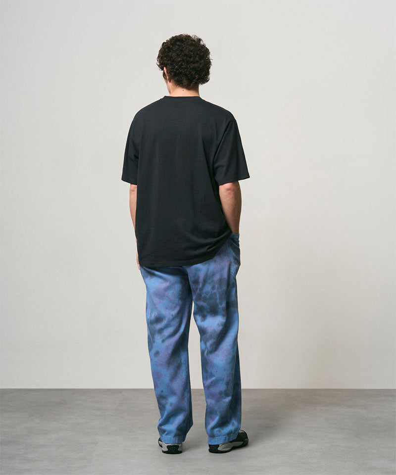 Back view of a model wearing a vintage black Gramicci One Point Tee and blue pants on a light-tone background.
