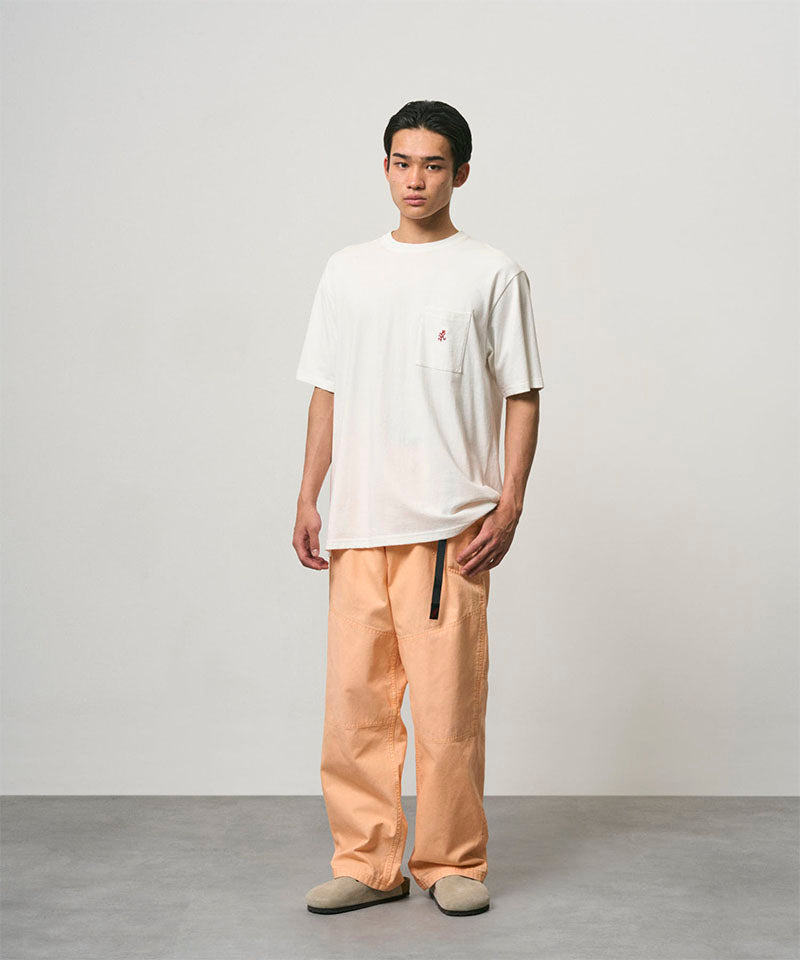 Model wearing a white Gramicci One Point Tee and orange pants on a light-tone background.