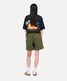Back view of a model wearing a Gramicci G-Skort in the color olive and a black shirt on a light-tone background.