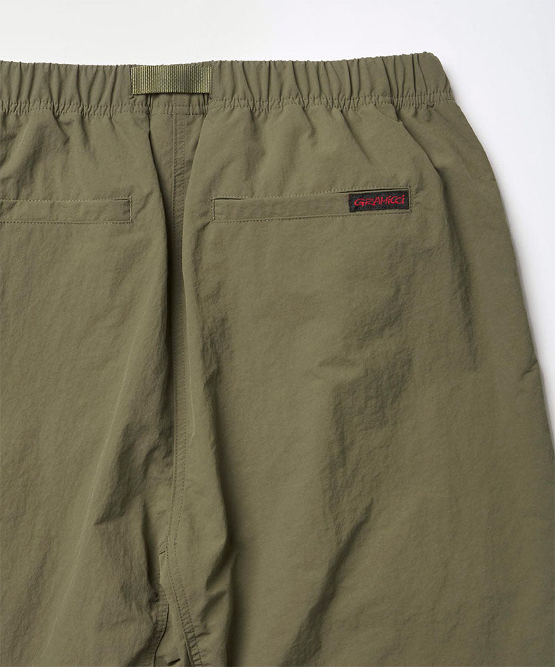 Close-up back view of burnt olive colored Nylon Gramicci Pants on a light-tone background.
