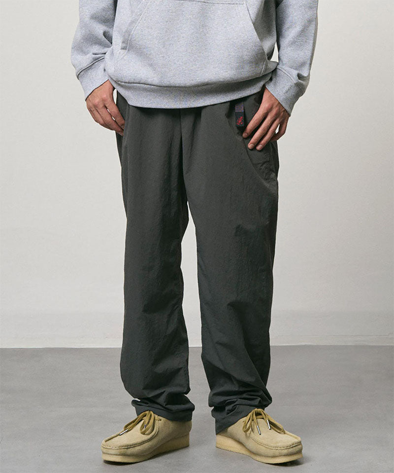 Model wearing carbon colored Nylon Gramicci Pants and a grey hoodie on a light-tone background.