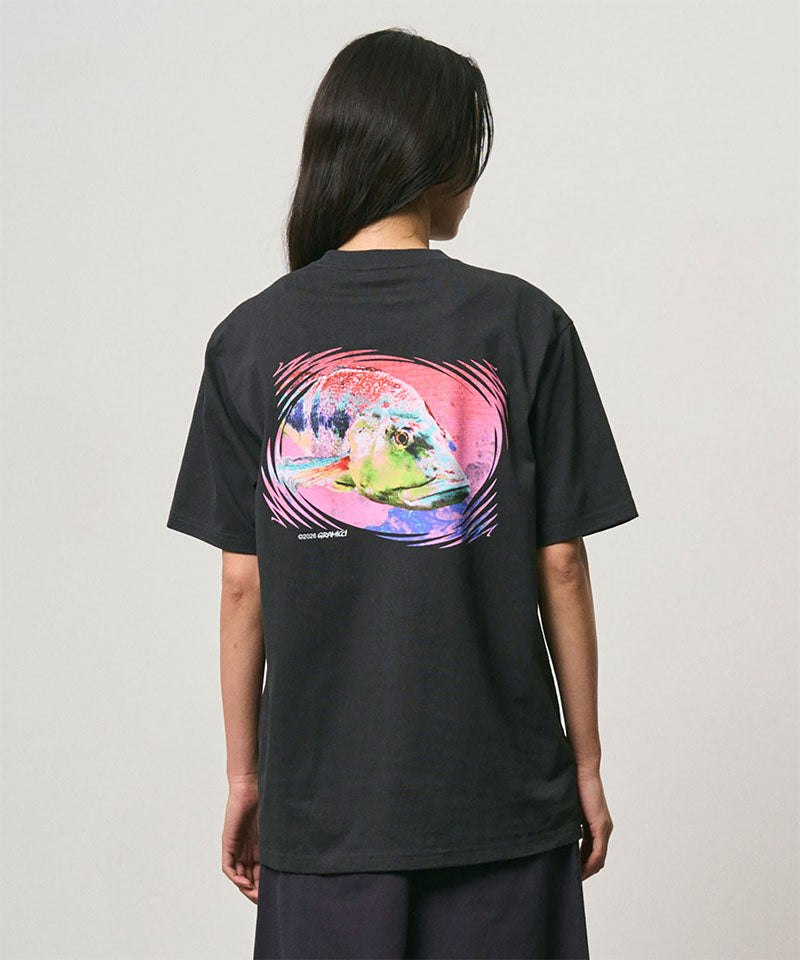 Back view of a model wearing a Gramicci vintage black Bass Tee with a graphic against a light-tone background.