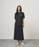 Model wearing a vintage black Gramicci Bass Tee and black skirt on a light-tone background.