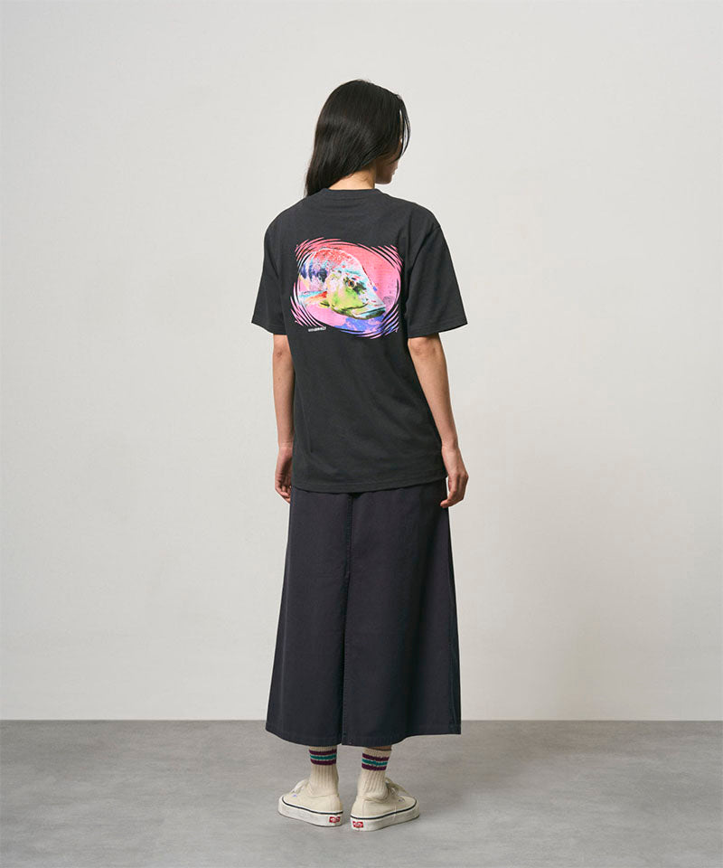 Back view of a model wearing a vintage black Gramicci Bass Tee with a graphic and black skirt on a light-tone background.