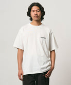 Model wearing a Gramicci white Bass Tee against a light-tone background.