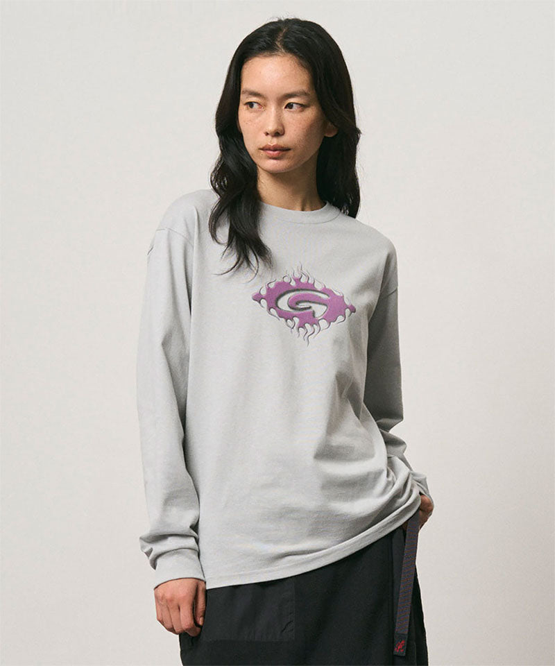 Model wearing a Gramicci mist colored Flames Long Sleeve Tee with a graphic against a light-tone background.