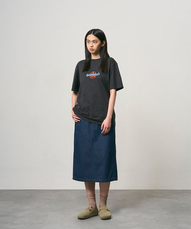 Model wearing a vintage black Gramicci Ladybug Tee with colorful graphic and blue skirt on a light-tone background.
