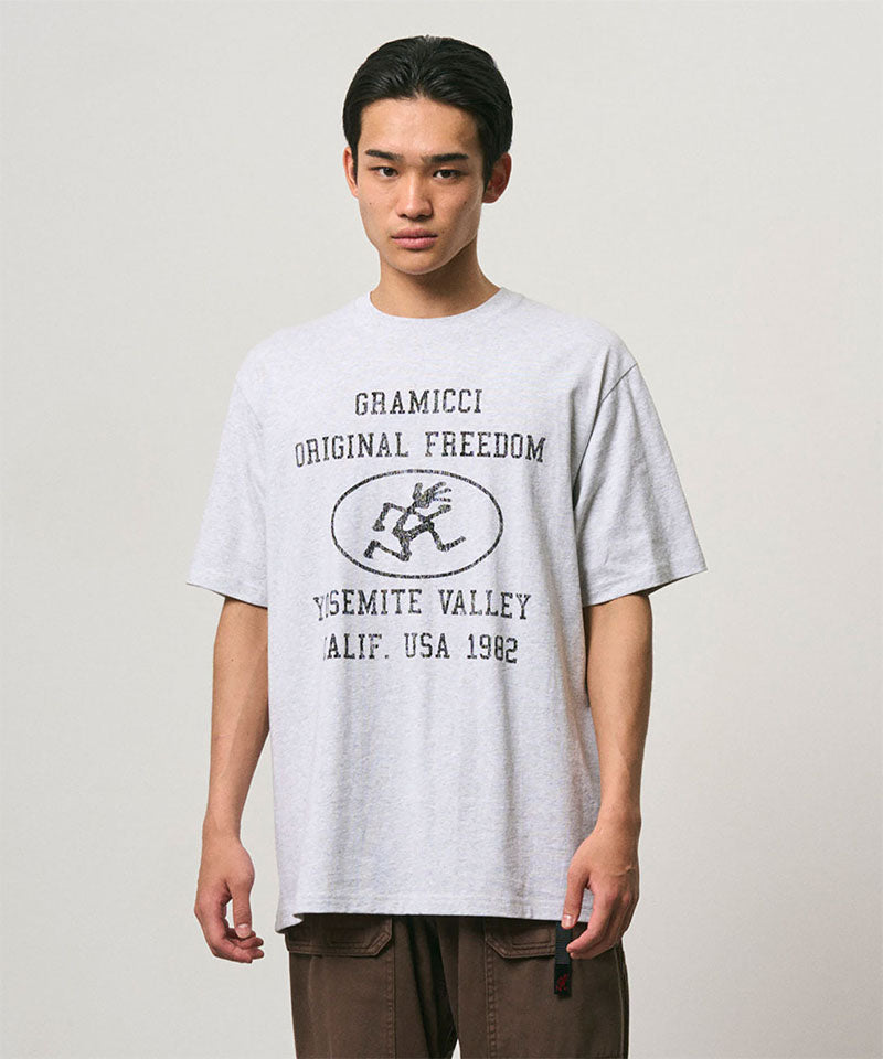 Model wearing a Gramicci ash heather colored Yosemite Valley Tee with a graphic against a light-tone background.