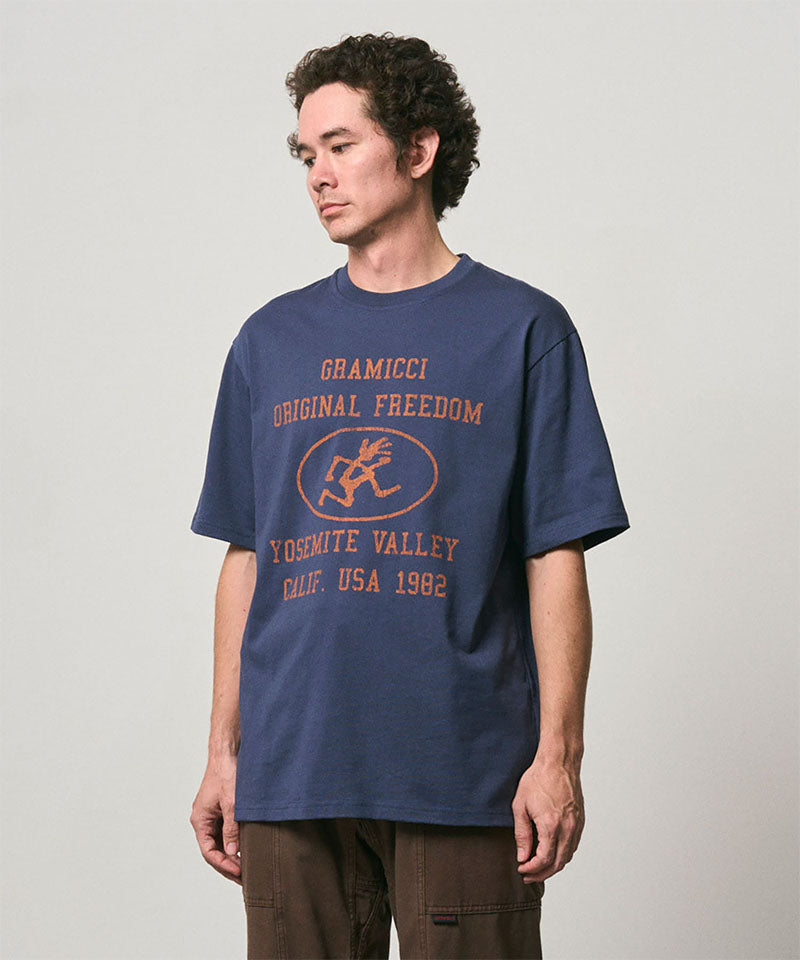Model wearing a Gramicci navy Yosemite Valley Tee with a graphic against a light-tone background.