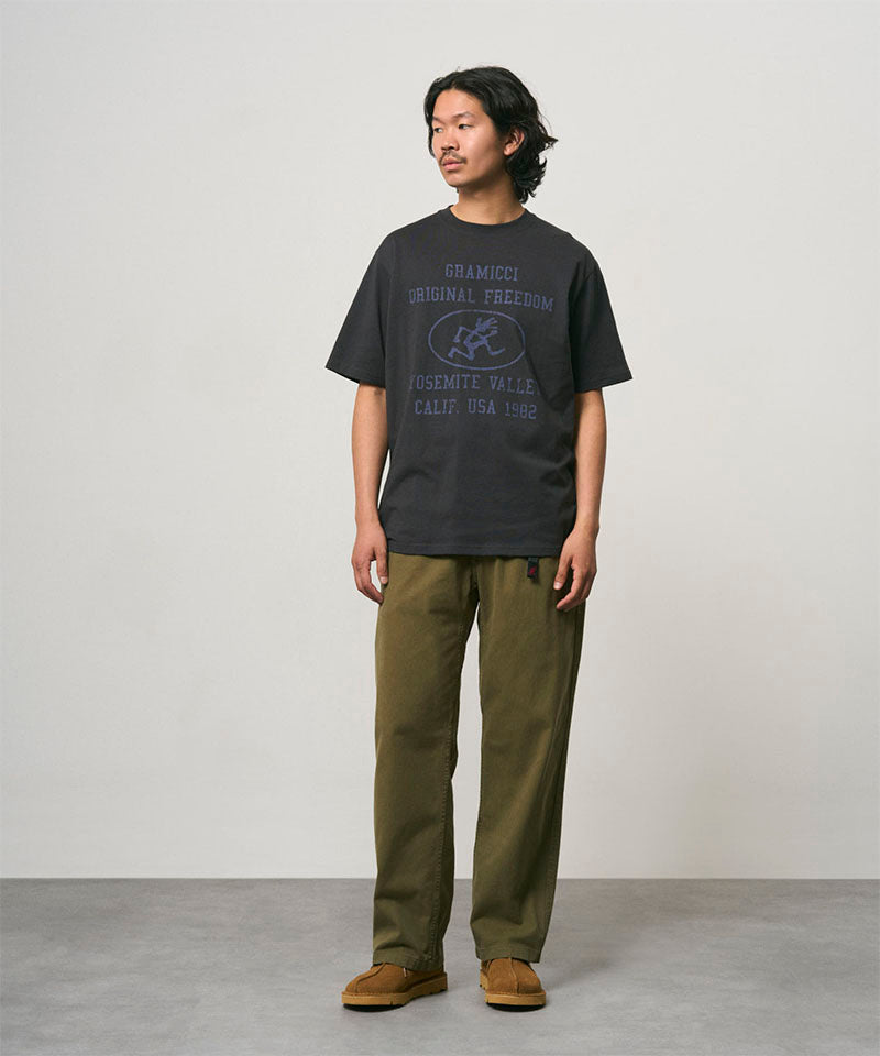 Model wearing a vintage black Gramicci Yosemite Valley Tee with a graphic and olive pants on a light-tone background.
