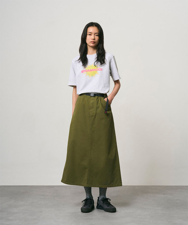 Model wearing a ash heather colored Gramicci Starburst Tee with a graphic and olive skirt on a light-tone background.