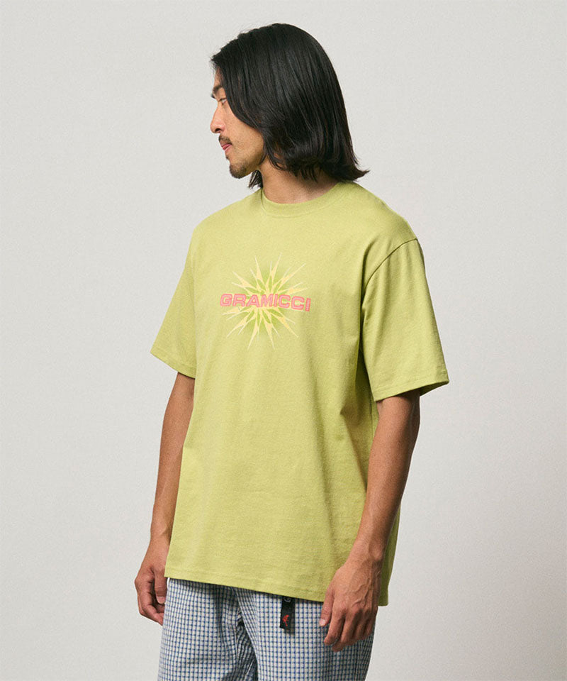 Model wearing a Gramicci sweet pea colored Starburst Tee with a graphic against a light-tone background.