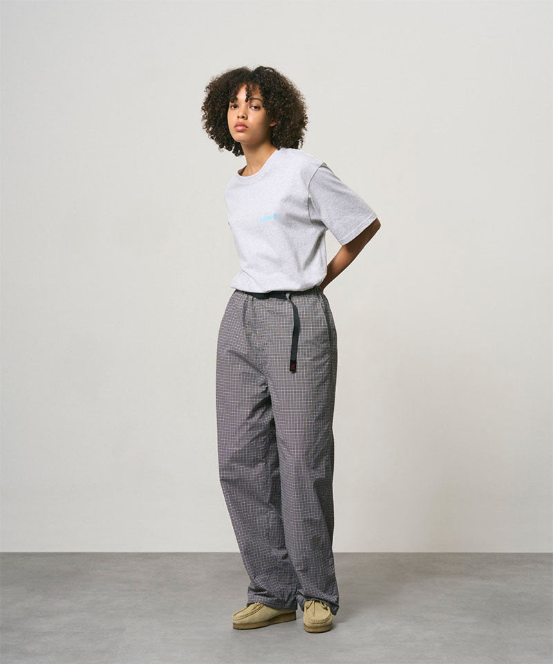 Model wearing a ash heather color Gramicci Joker Tee and grey pants on a light-tone background.