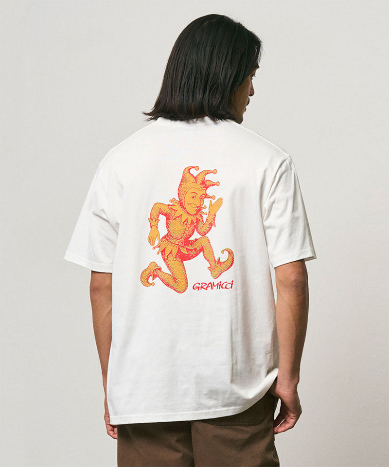 Model wearing a Gramicci white Joker Tee with an orange graphic against a light-tone background.