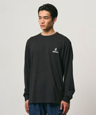 Model wearing a Gramicci black One Point Logo Long Sleeve Tee with a graphic against a light-tone background.