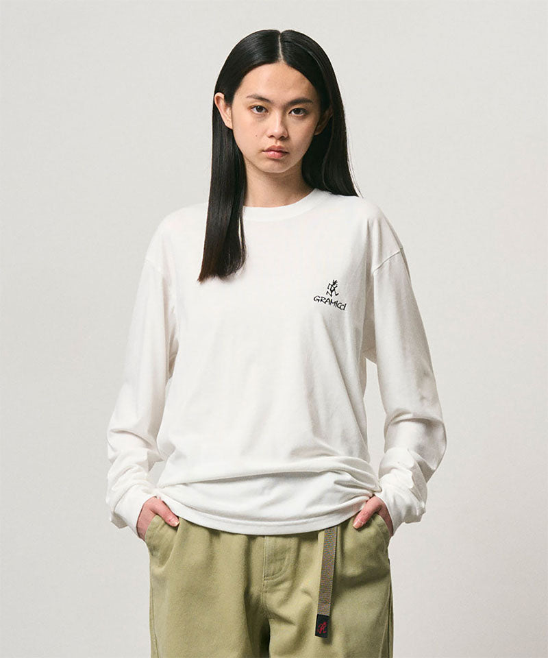 Model wearing a Gramicci white One Point Logo Long Sleeve Tee with a graphic against a light-tone background.