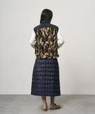 Model wearing a indigo Gramicci G-Zero Primaloft Skirt and a black and brown camo vest on a light-tone background.