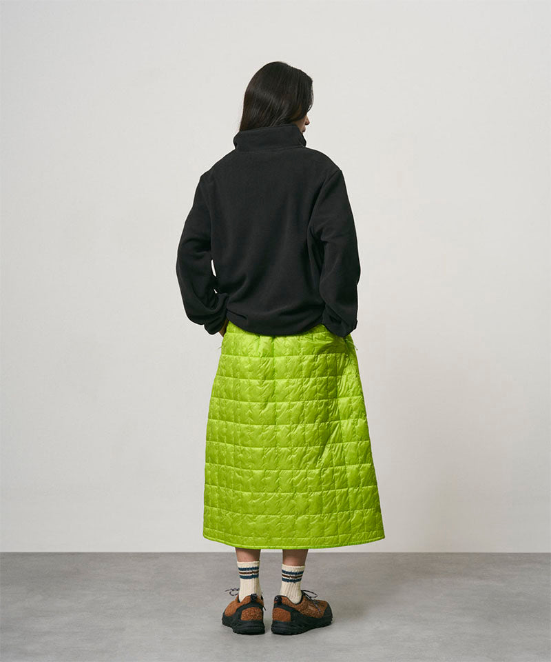 Model wearing a lime colored Gramicci G-Zero Primaloft Skirt and a black  jacket on a light-tone background.
