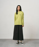 Model wearing a black Gramicci 5-Pocket Skirt and a lime green shirt on a light-tone background.
