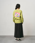 Back view of a model wearing a black Gramicci 5-Pocket Skirt and a lime green shirt on a light-tone background.
