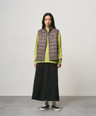Model wearing a black Gramicci 5-Pocket Skirt and a brown vest on a light-tone background.