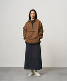 Model wearing a double navy Gramicci 5-Pocket Skirt and a brown jacket on a light-tone background.
