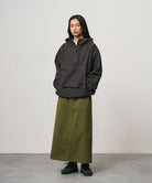 Model wearing a olive colored Gramicci 5-Pocket Skirt and a dark grey jacket on a light-tone background.