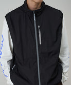 Model wearing a Gramicci black Flyweight Vest against a light-tone background.