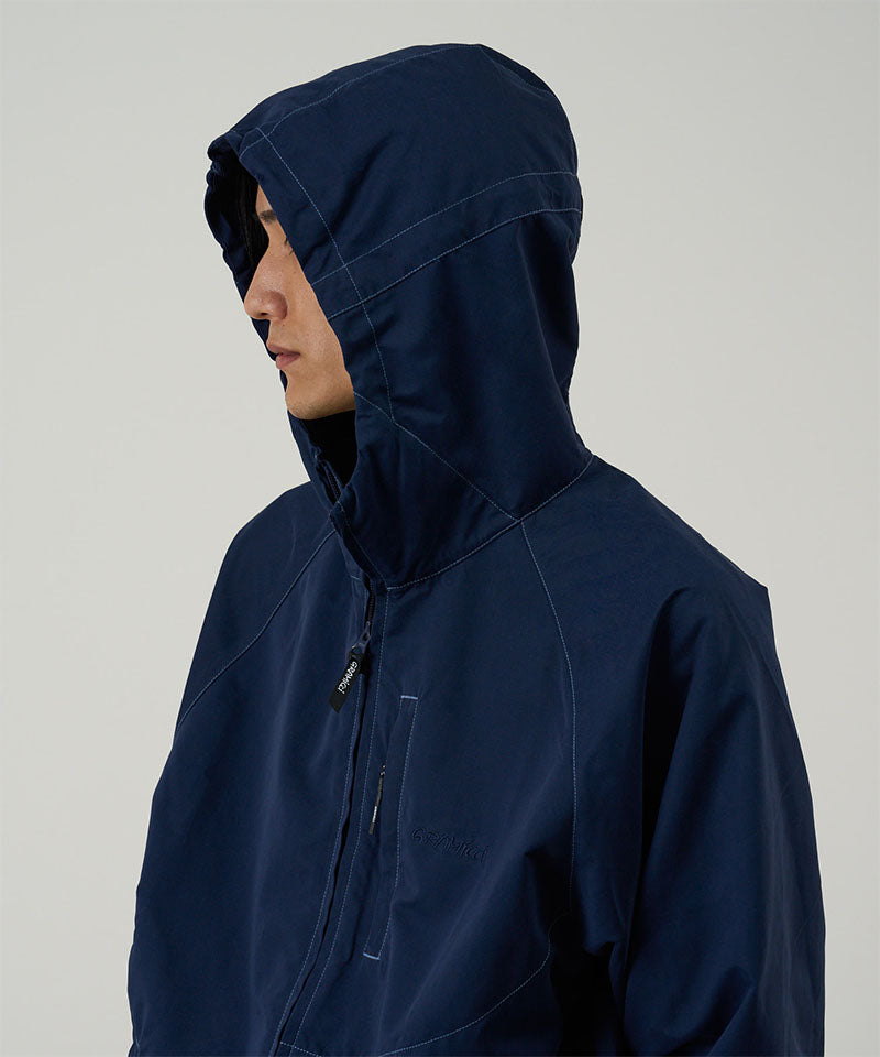 Model wearing a Gramicci dark navy Milton Hooded Jacket against a light-tone background.