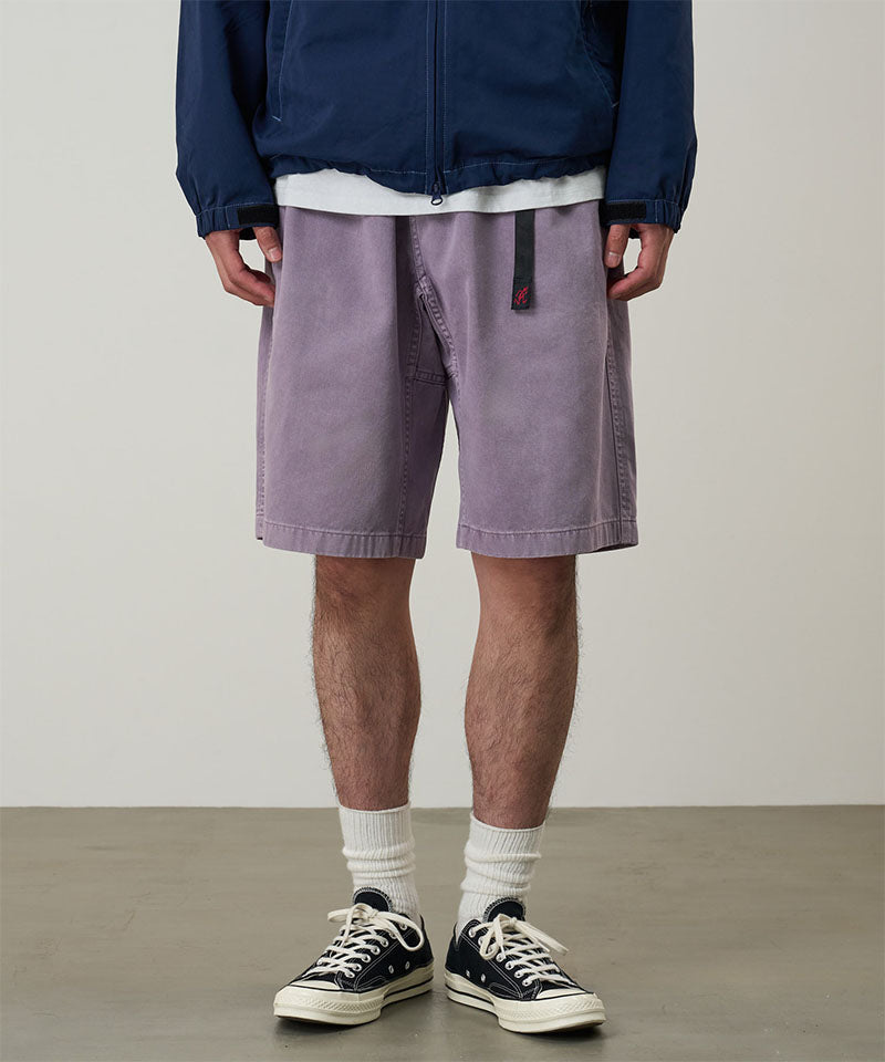 Model wearing a Gramicci Natural Dyed Jam Short in the color purple on a light-tone background.
