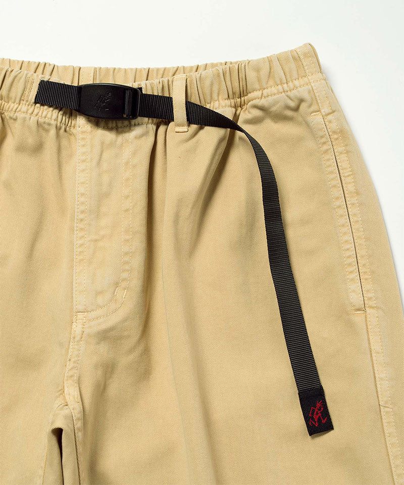 Close-up of Natural Dyed Gramicci Pant Straight Fit in the color chino with a black belt against a light-tone background.
