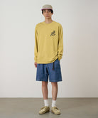 Model wearing blue Gramicci Japanese Chambray Shorts and a yellow shirt on a light-tone background.