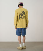Back view of a model wearing blue Gramicci Japanese Chambray Shorts and a yellow shirt on a light-tone background.