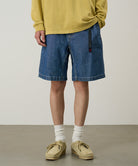 Model wearing blue Gramicci Japanese Chambray Shorts and a yellow shirt on a light-tone background.