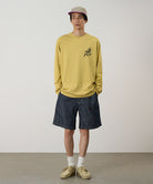 Model wearing navy Gramicci Japanese Chambray Shorts and a yellow shirt on a light-tone background.