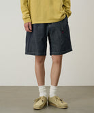 Model wearing navy Gramicci Japanese Chambray Shorts and a yellow shirt on a light-tone background.