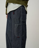 Model wearing navy Japanese Chambray Rock Slide Pants and a moss green jacket on a light-tone background.